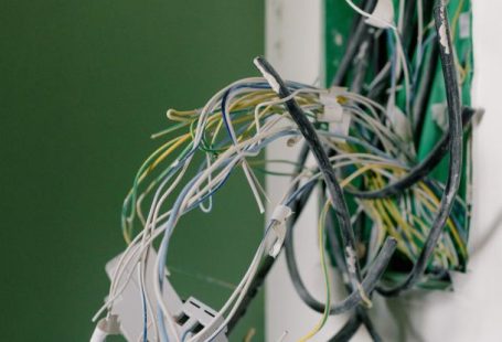 Home Maintenance - Opened power socket with various wires on white wall during repair at home